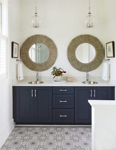 Luxury Bathroom with Navy Cabinets, Dual Sinks, and Patterned Tile by Allen Patterson Builders.