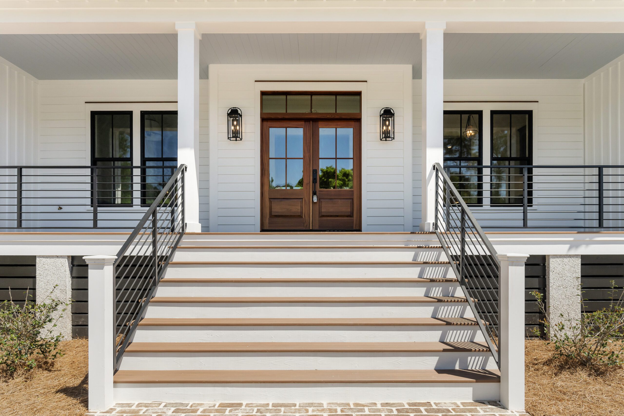 Home Facade with White Siding, Wooden Doors, and A Metal Roof by Allen Patterson Builders.