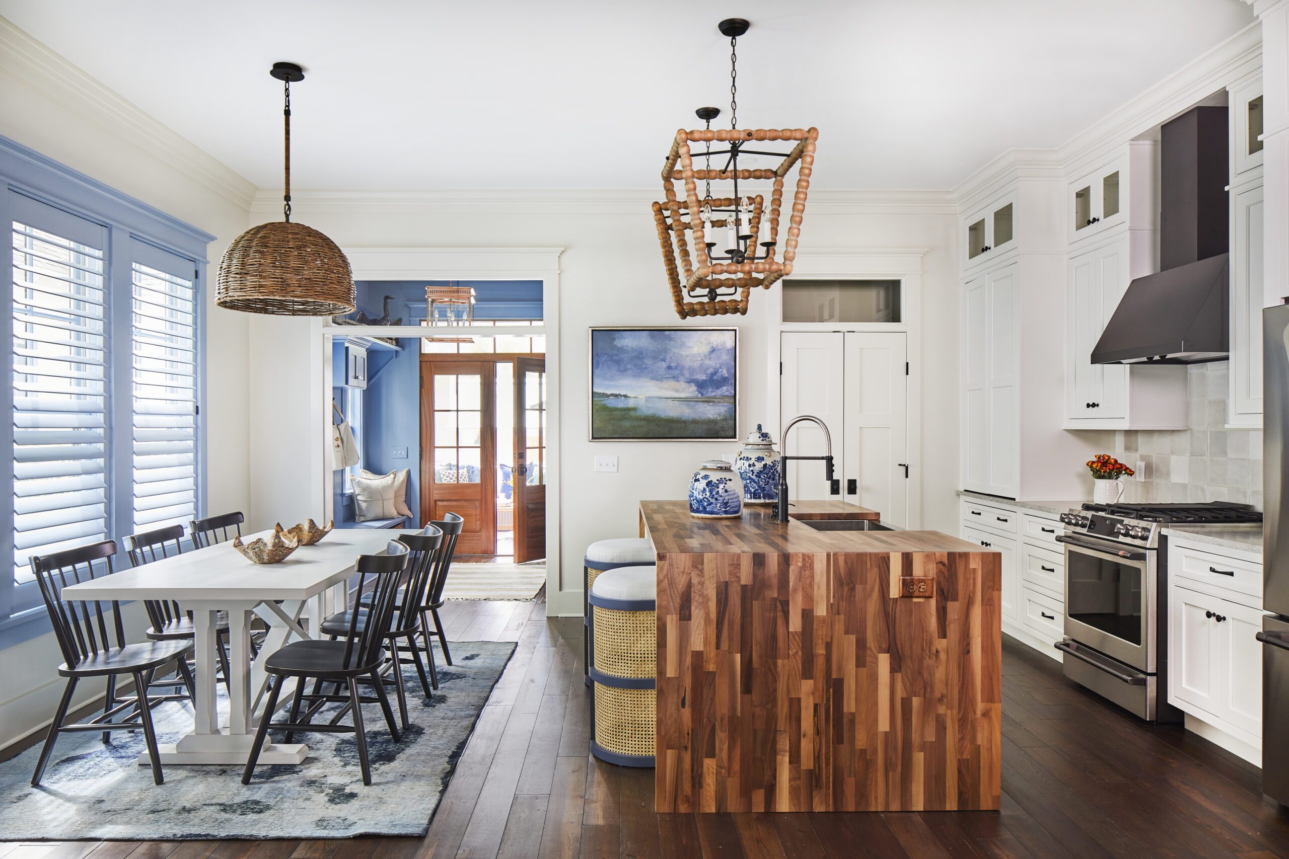 Open-concept kitchen and dining area in the 2020 Southern Living Showcase Home in Habersham, Beaufort, SC, featuring a butcher block waterfall island, white Wellborn cabinetry, and a wood-bead lantern chandelier.