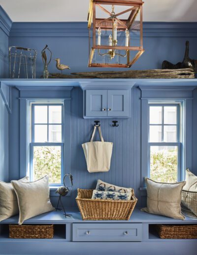 Blue built-in mudroom with a window-flanked bench, beadboard wall, and copper lantern pendant in the 2020 Southern Living Showcase Home in Habersham, Beaufort, SC.