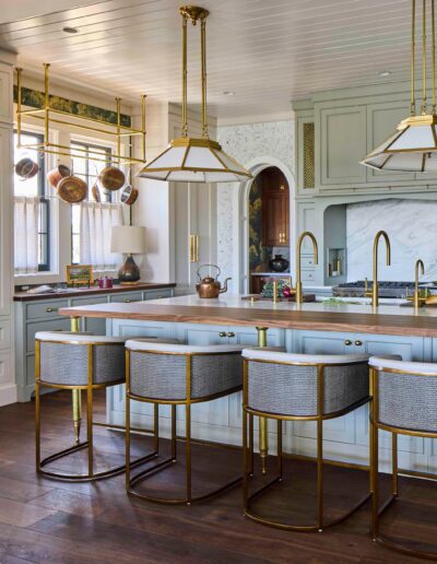 Custom kitchen detail in the Habersham Showcase Home with copper pots hung over a window, brass faucet, and pale blue cabinetry, Habersham, SC