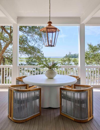 Covered waterfront porch in the Habersham Showcase Home with a round dining table, woven chairs, copper lantern, and marsh views of the Lowcountry, Habersham, SC