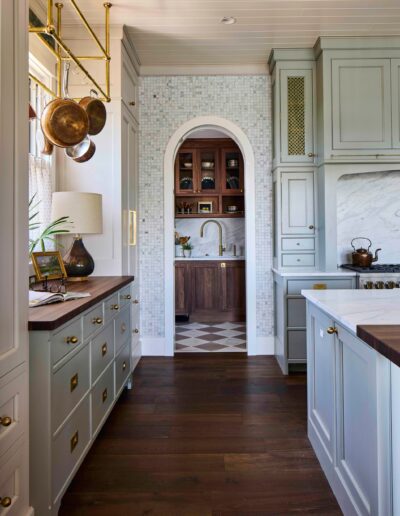 Kitchen with sage-green cabinetry, marble counters, and a brass pot rack in the 2025 Southern Living Showcase Home in Habersham, SC, built by Allen Patterson Builders