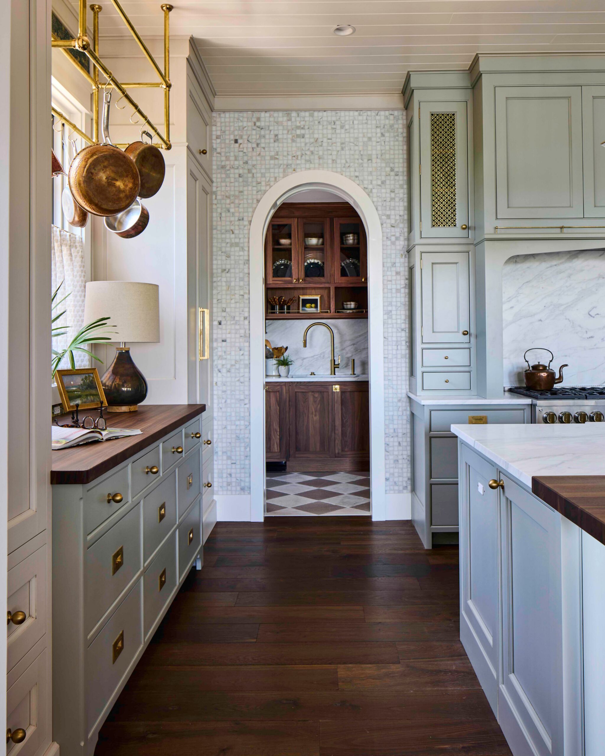 Kitchen with sage-green cabinetry, marble counters, and a brass pot rack in the 2025 Southern Living Showcase Home in Habersham, SC, built by Allen Patterson Builders