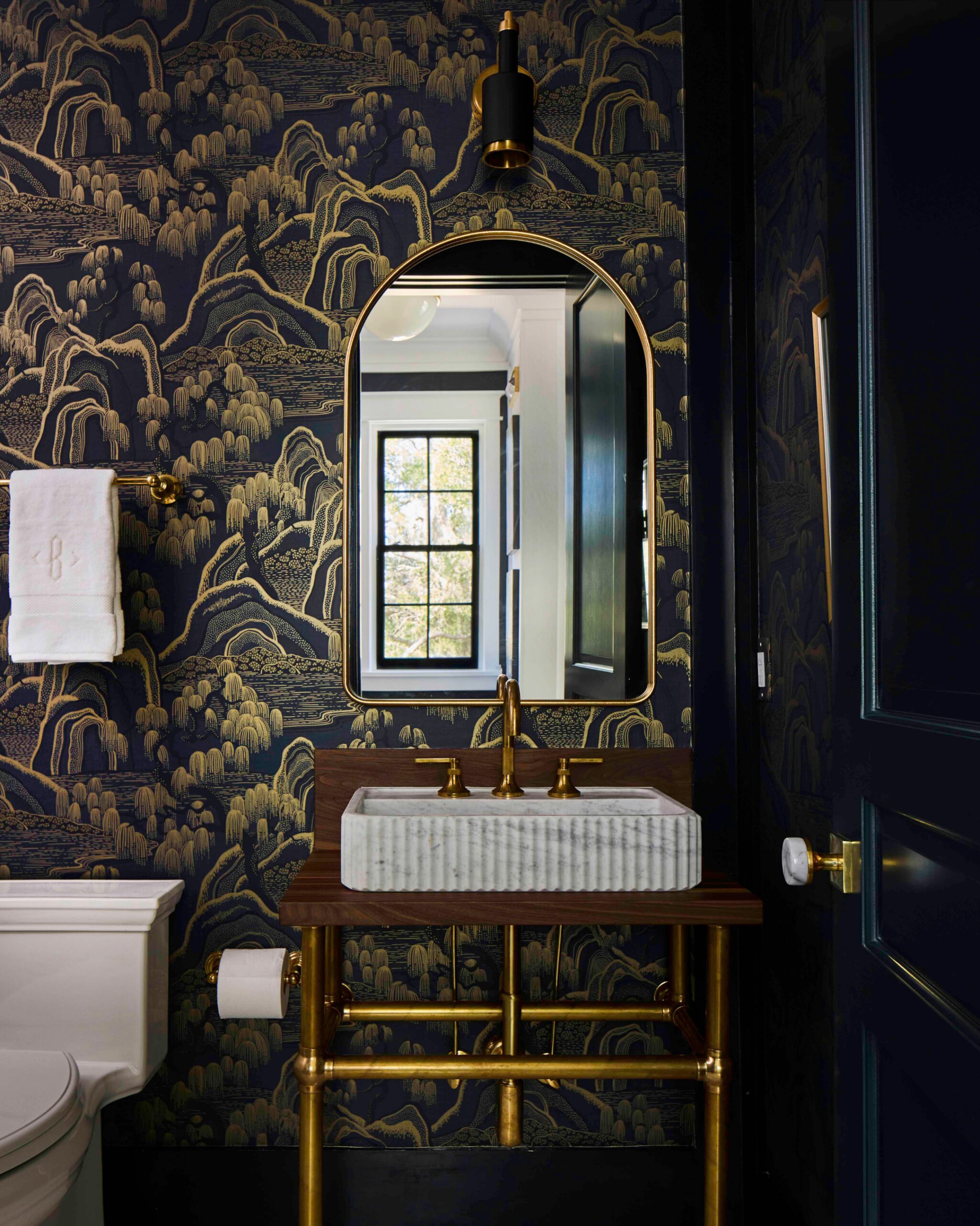 Powder room with dark scenic wallpaper, a fluted marble sink, and brass fixtures in the 2025 Southern Living Showcase Home in Habersham, SC, built by Allen Patterson Builders