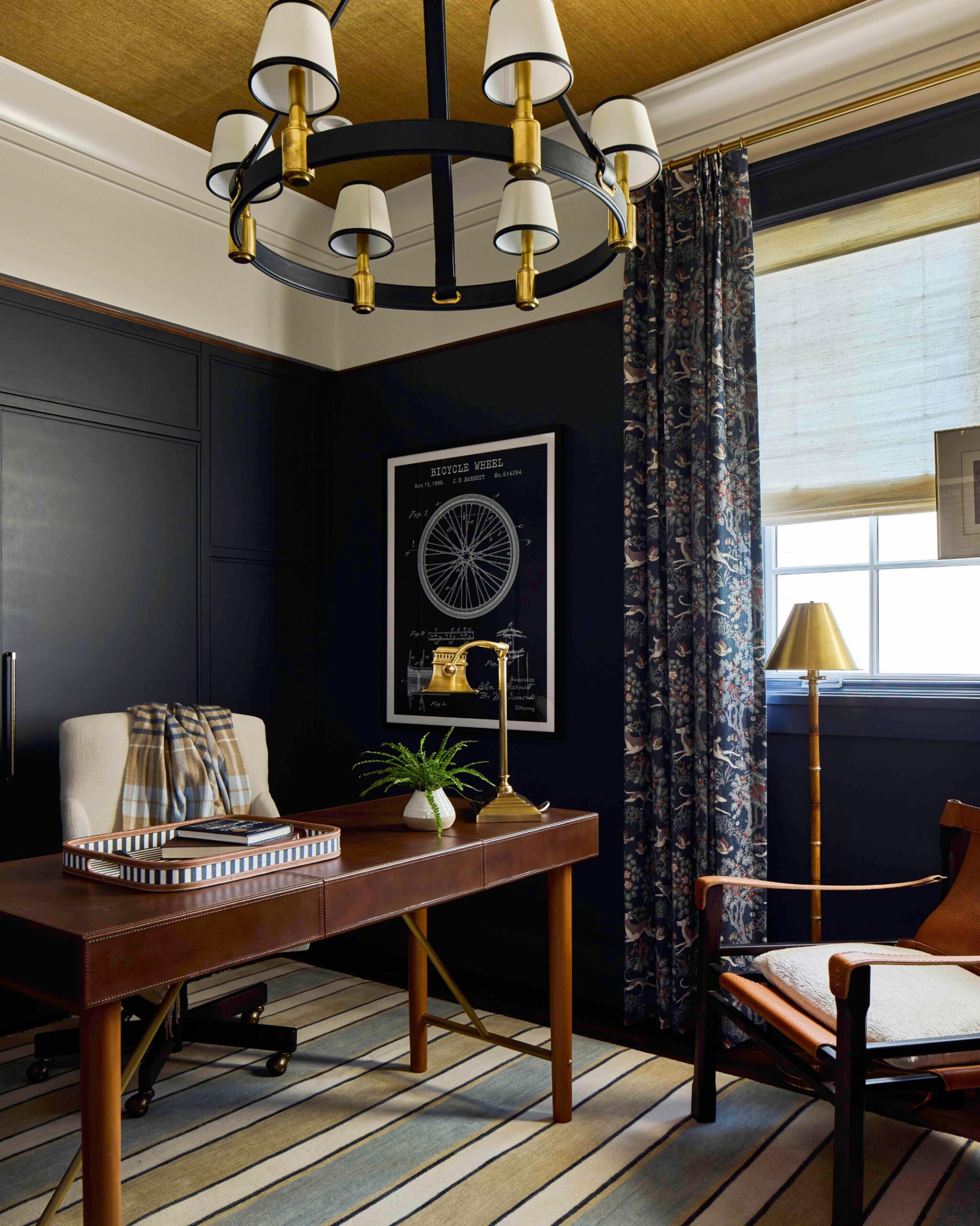 Home office with navy paneled walls, a brass chandelier, and a leather desk in the 2025 Southern Living Showcase Home in Habersham, SC, built by Allen Patterson Builders