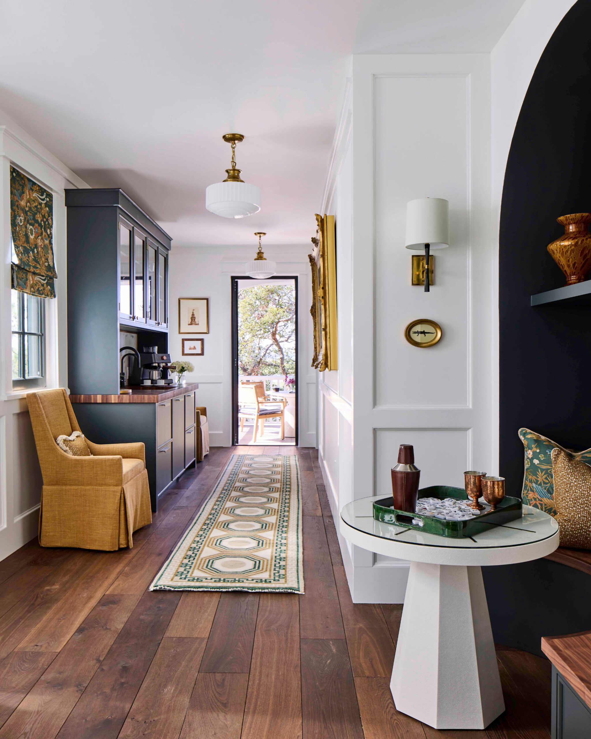Hallway and bar area with hardwood floors, schoolhouse pendants, and a porch view in the 2025 Southern Living Showcase Home in Habersham, SC, built by Allen Patterson Builders