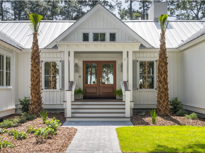 Home Facade with White Siding, Wooden Doors, and A Metal Roof by Allen Patterson Construction.